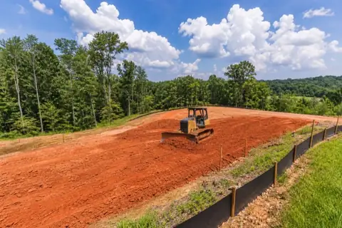 Excavator shaping a High Point site with red Piedmont soil and stabilized drainage controls